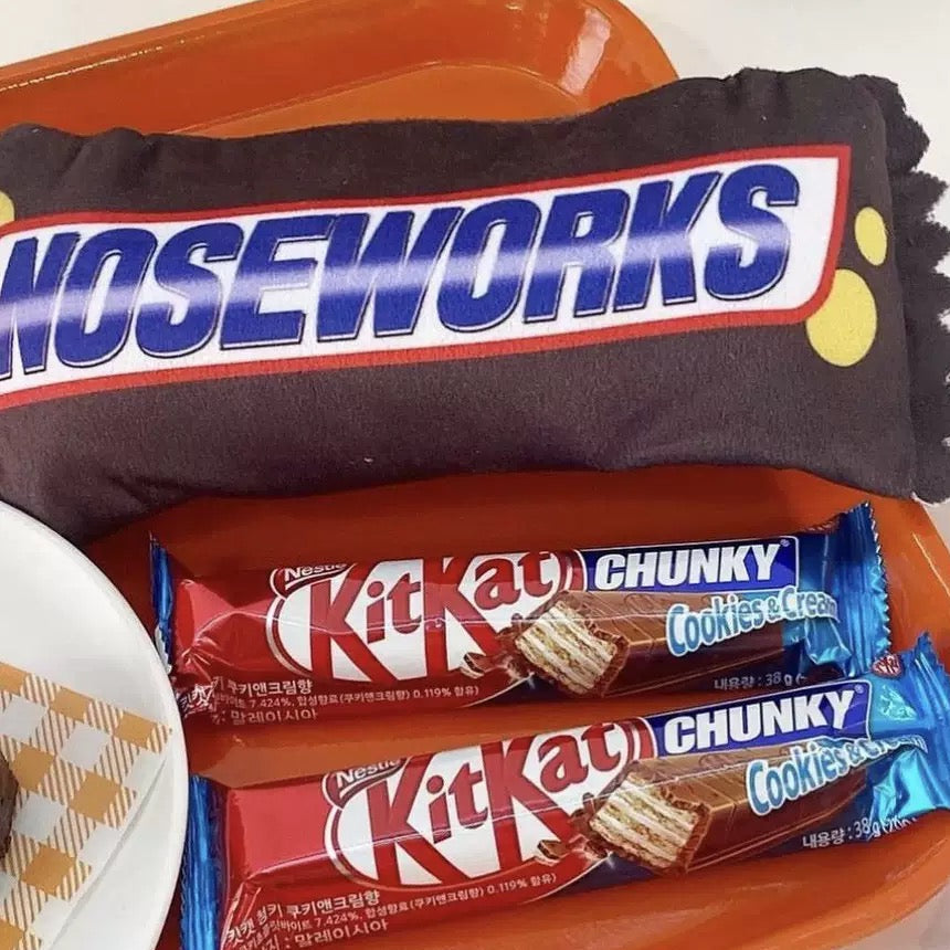 Noseworks candy bar and Kit Kat Chunky cookies & cream bars on a white surface.