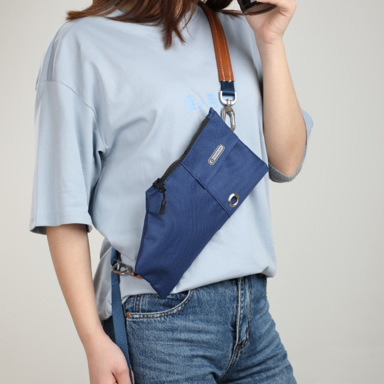 Person wearing a blue crossbody bag with a plain background