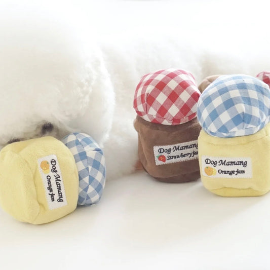 Plush dog toy designed to look like a jam can, in various colors with checkered patterns, intended for hide-and-seek play.