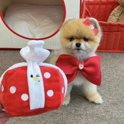 Small dog wearing a red bow tie standing next to a red and white plush toy.