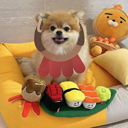 Dog wearing a lion costume with toy food items on a yellow cushion
