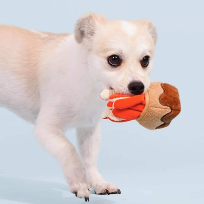Dog holding a toy shaped like a hot dog against a light blue background